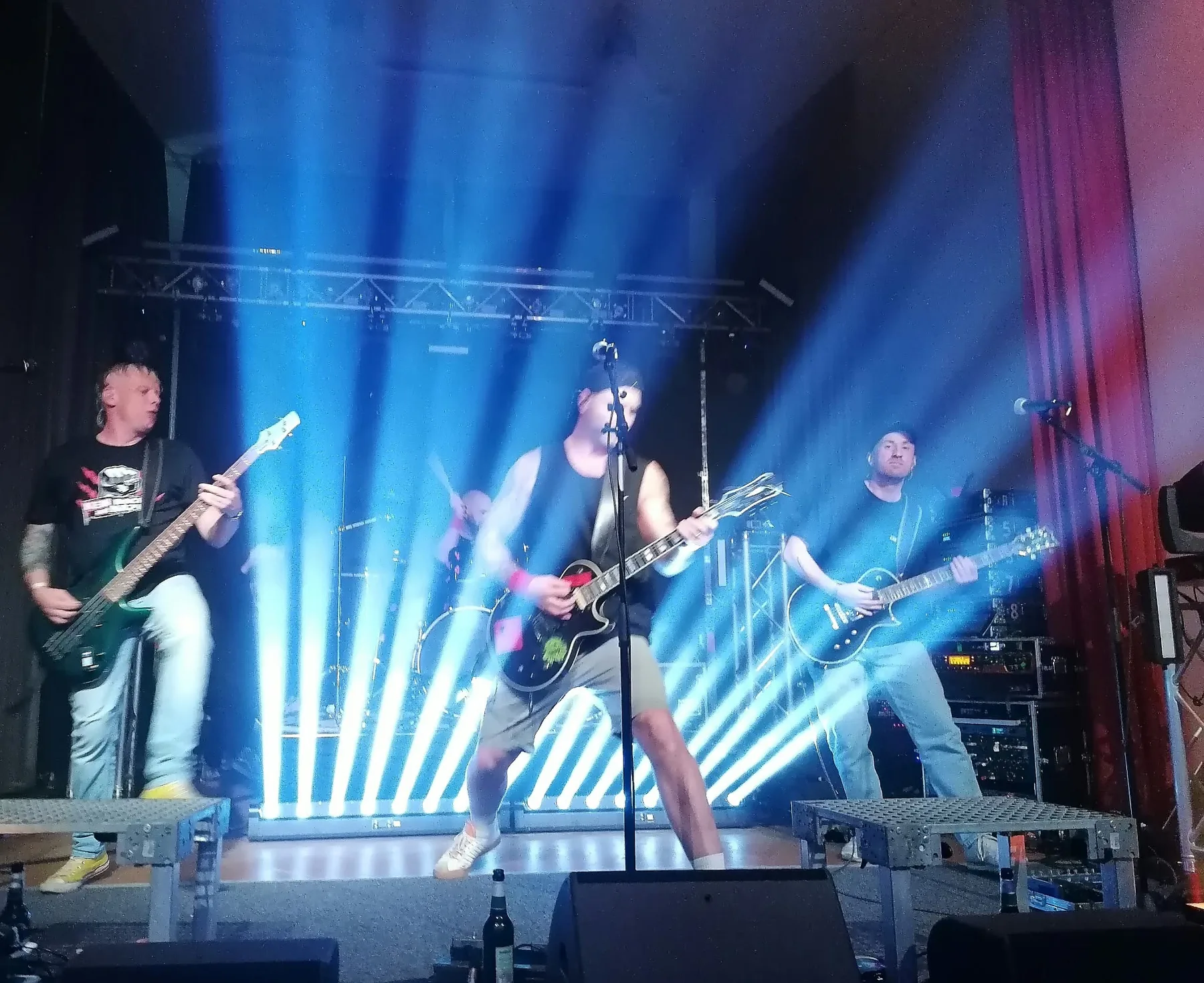 Rockband auf der Bühne vor blauen Lichtstrahlen